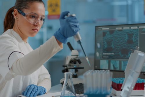 Chemist working on experiment with micro pipette and beaker, using dropper on test tube to develop science industry in laboratory. Woman scientist doing lab work with equipment and tools.