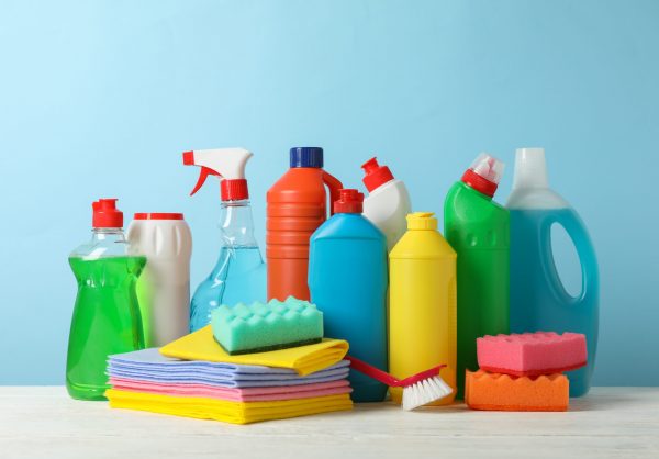 Bottles with detergent and cleaning supplies on blue background, space for text